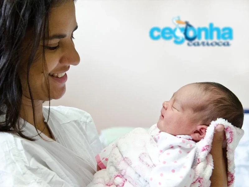 Mãe segurando bebê recém-nascido ao lado da marca Cegonha Carioca