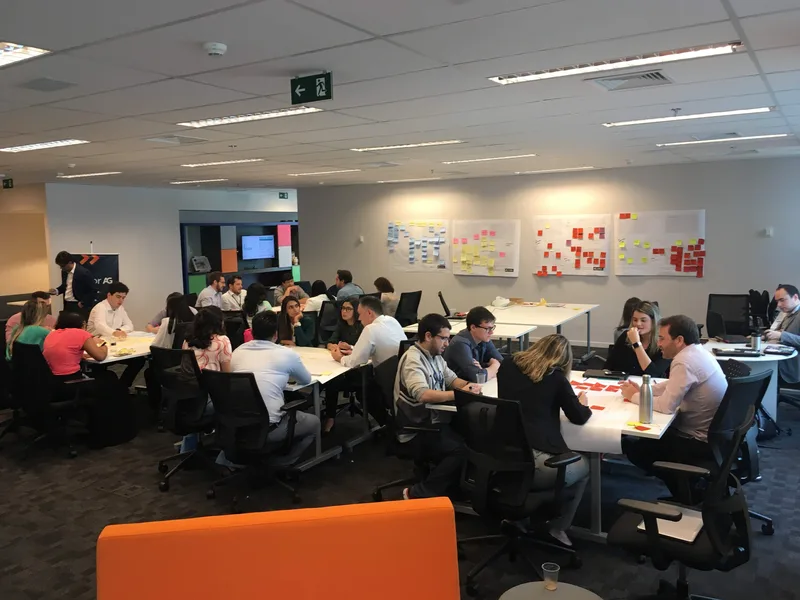 Facilitação da Binky em sala de planejamento com grupo em torno de canvas na parede